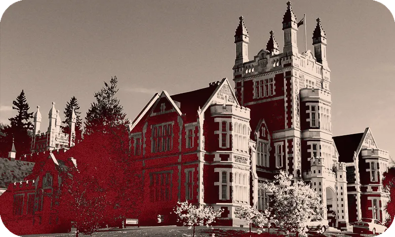 Black and white photograph of a castle-like building, washed with a dark red colour
