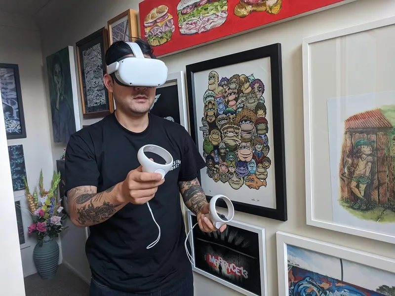 bobby hung wears a VR headset in a hallway lined with pieces of art