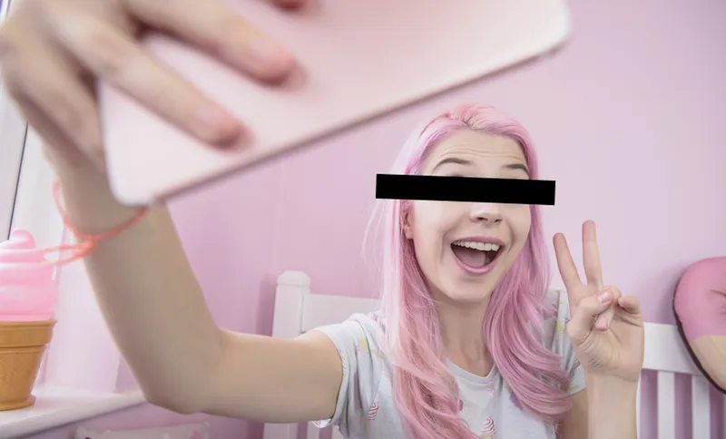Young woman making peace sign posing towards smartphone in bedroom