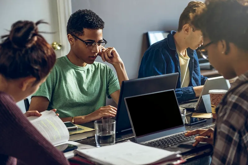 Female and male friends studying together in living room - stock photo