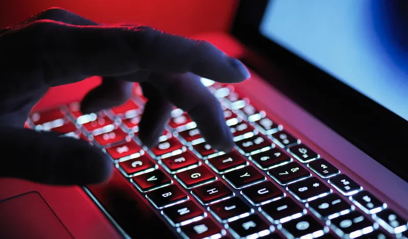 A dark mystery hand typing on a laptop computer at night