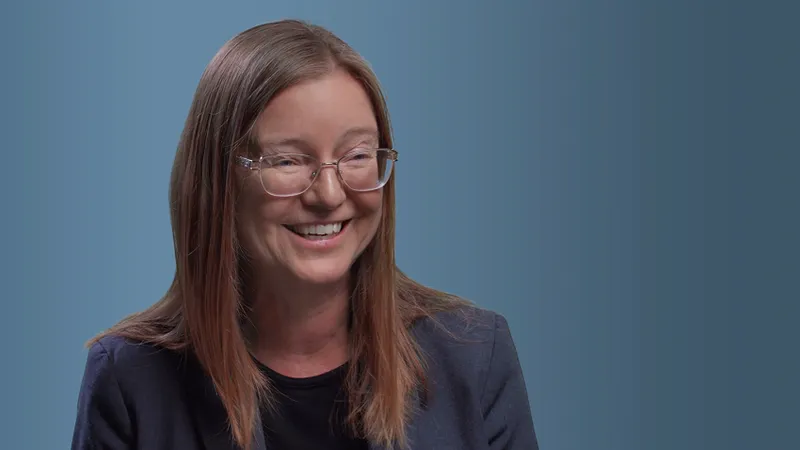 lisa ellis, a smilling white woman with medium length brown hair and a smile with a blue background