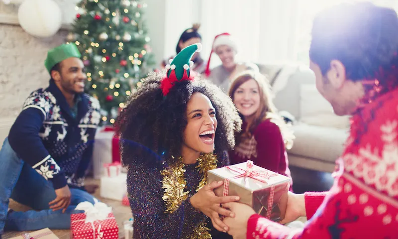 Enthusiastic friends exchanging Christmas gifts