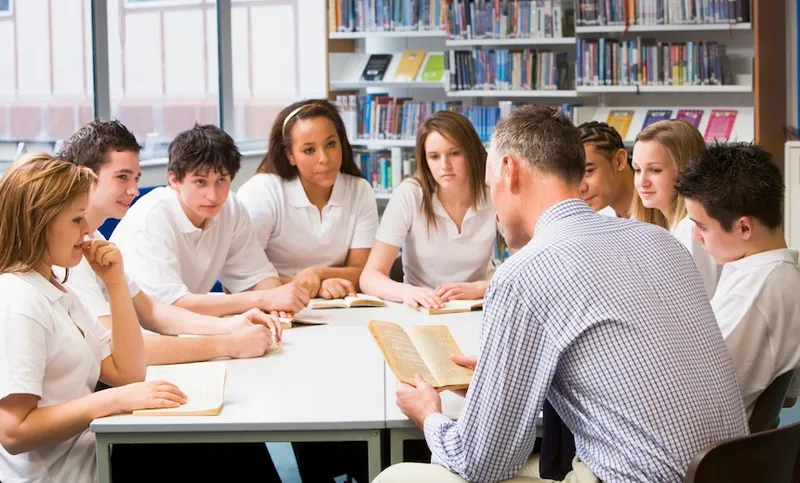 Schoolchildren and teacher studying in school library