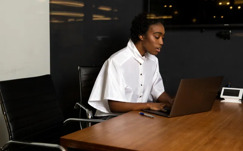 A non-binary person using a laptop at work.