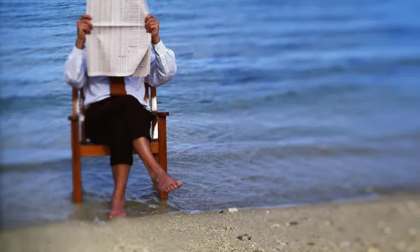 reading newspaper at beach stock getty