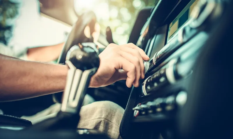 person adjusting dial on car radio