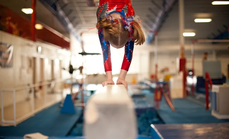 Young Gymnast Doing Handstand on Balance Beam