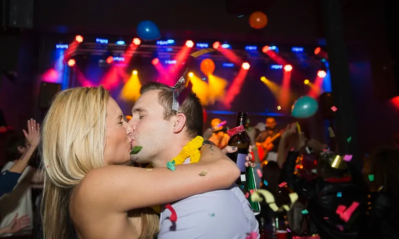 Confetti falling kissing couple enjoying New Year celebration