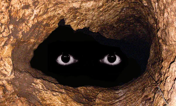 a deep, dark cave with a pair of scary eyes floating in it