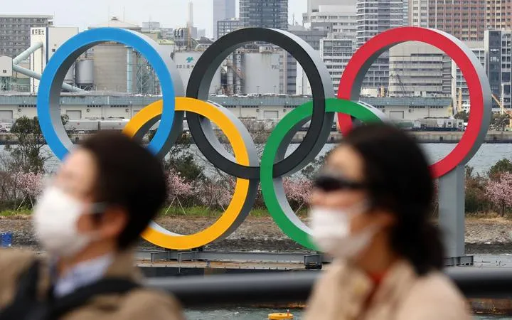 People wearing a mask walk near the Olympics' mark in Odaiba, Tokyo, amid the outbreak of a new coronavirus in Japan.