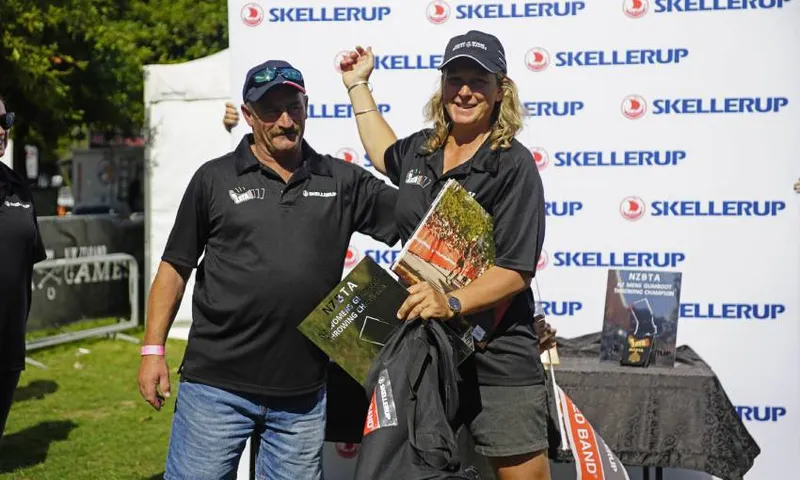 blonde woman (kristin churchward) and a man with sunglasses on his hat (curly troon) stand iin the sun