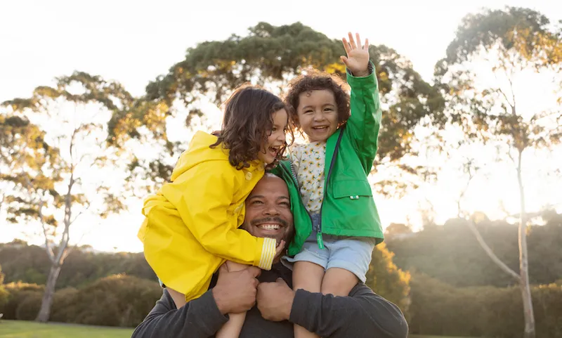 Twin sisters have fun as father holds them on his shoulders