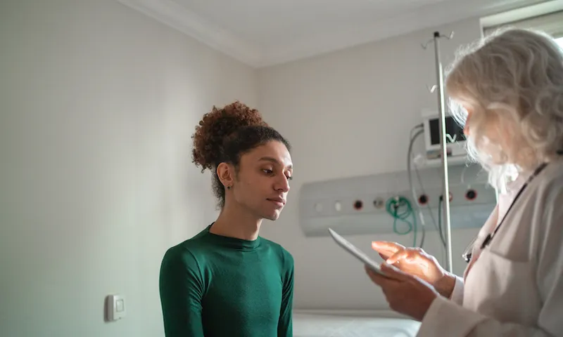 Doctor talking to patient at hospital room with digital tablet