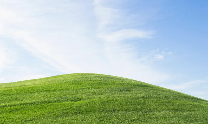 Rolling green hill under blue sky