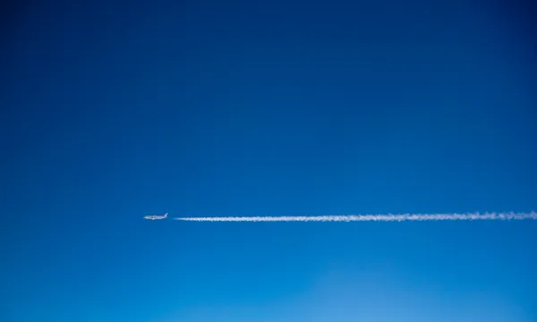 Blue sky, a plane leaving white vapour trails