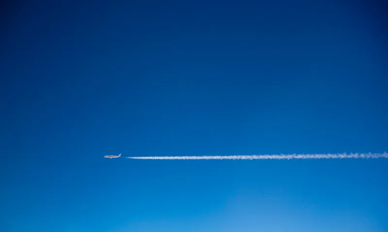 Blue sky, a plane leaving white vapour trails