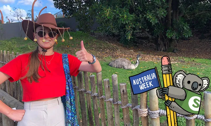 Author pulls a thumbs up in front of an emu. An illustration of a koala holding a pencil and flying an "Australia Week" flag is in the foreground.