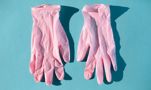 Pink protective gloves for doctor on blue background