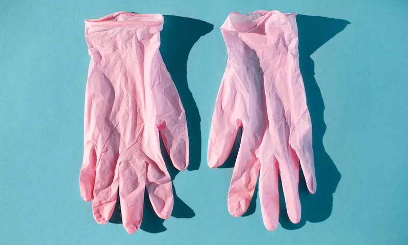 Pink protective gloves for doctor on blue background