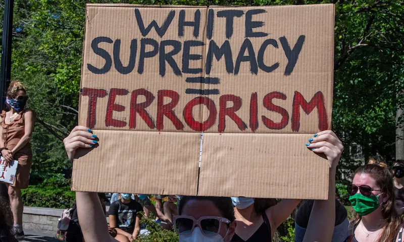 A protester holds a placard with a protest message reading “