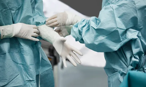 Female doctor helping surgeon wearing glove
