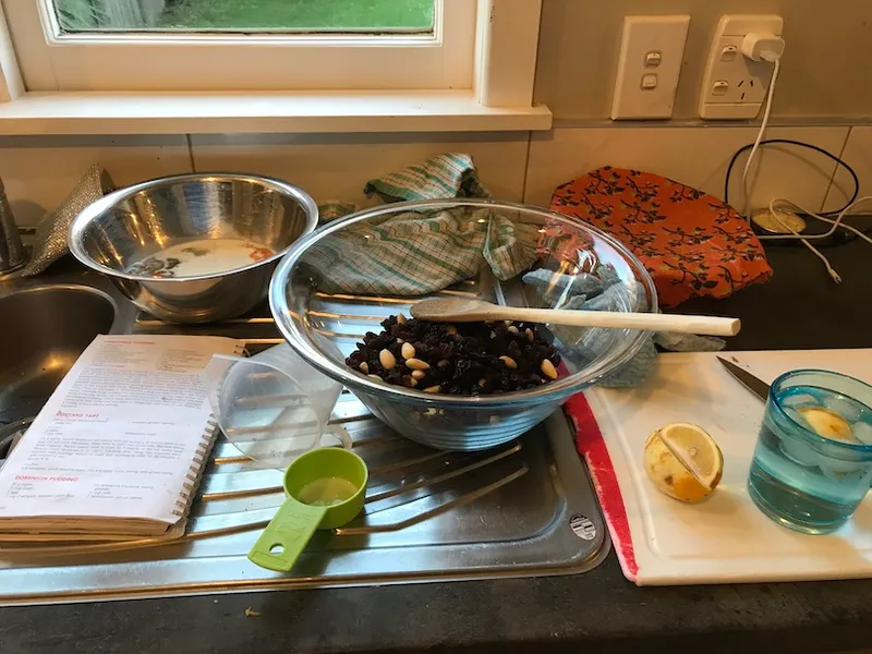 Bowls and measuring spoons, etc, on a bench. A drink and lemon to one side.