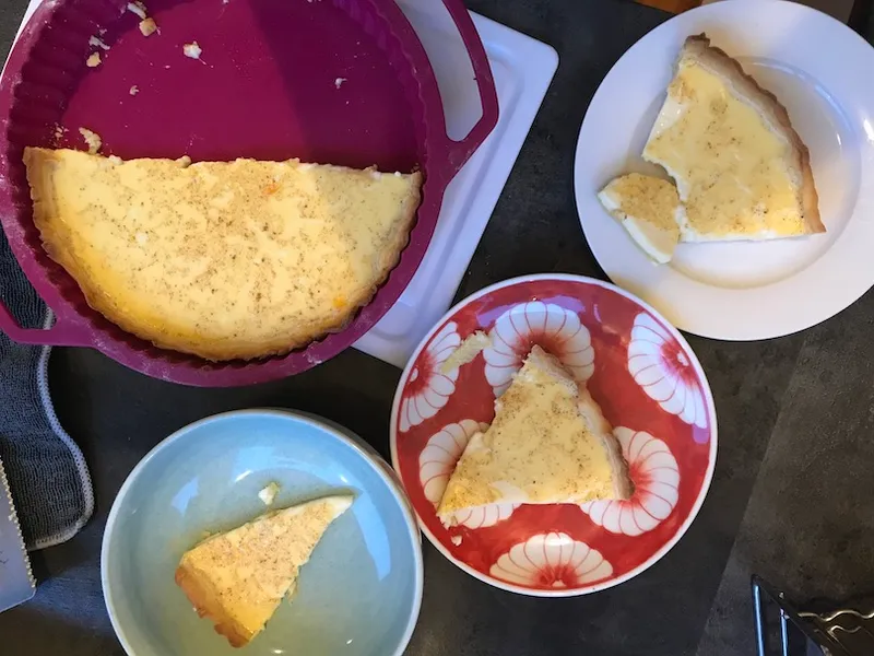 A flan dish with half a custard tart in it, surrounded by plates with wedges of tart.