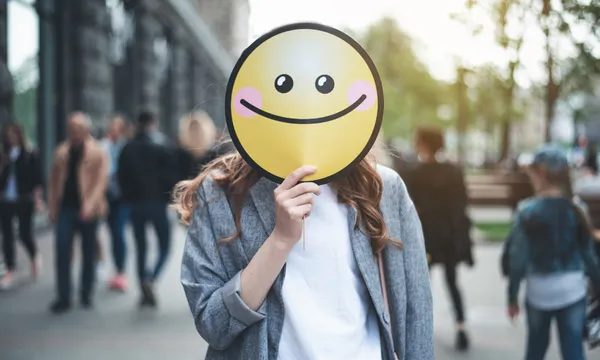 Woman holding smiling sign on her face outside smile street