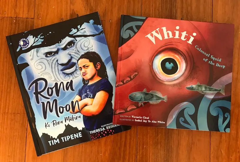 Two picture books, Rona Moon and Whiti, on a wooden floor