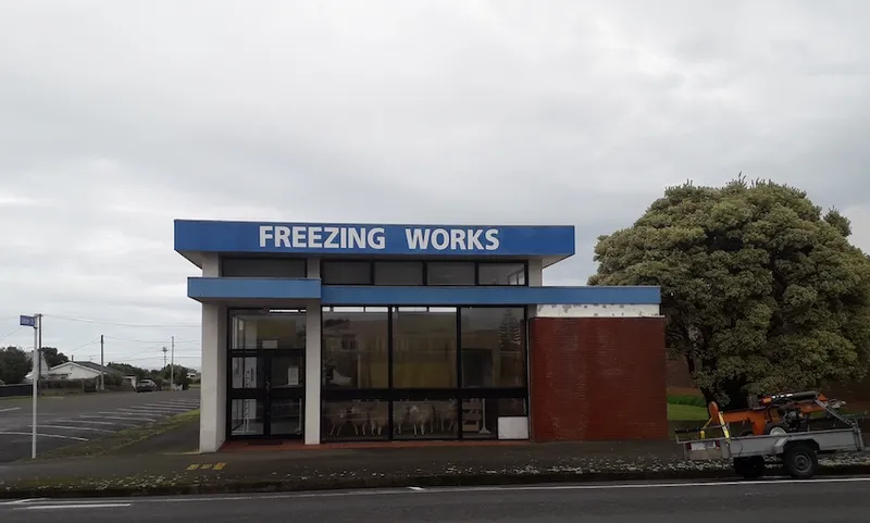 Photograph of a grey day in Pātea, view of an old building with FREEZING WORKS painted on the side