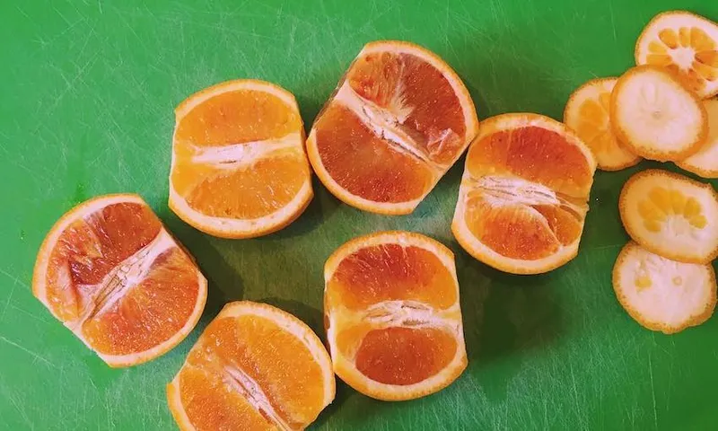 Blood oranges, sliced in half, on an emerald-green chopping board