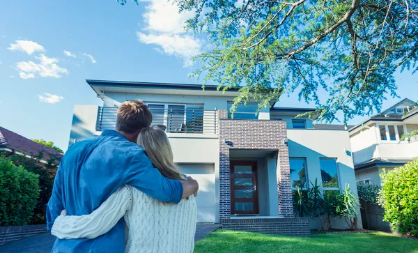 Couple standing in front of their new home.