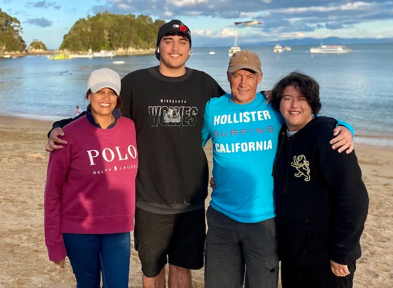 A family of four, with two adult children, photographed on a golden-sand NZ beach.