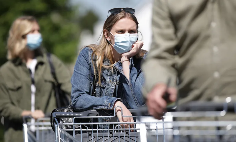 People in masks wait in a supermarket queue