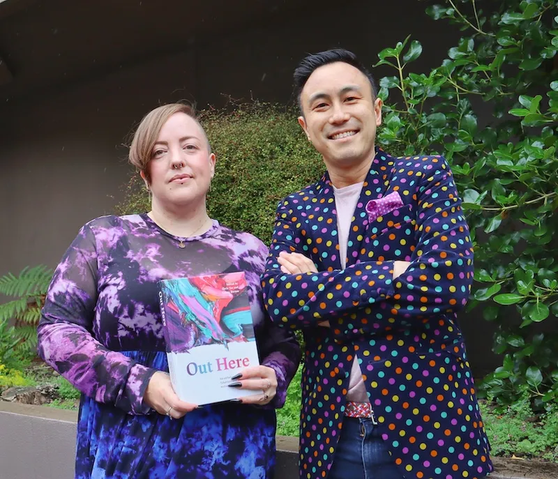 Two radiant poets, dressed in purple finery, holding a copy of their new book.