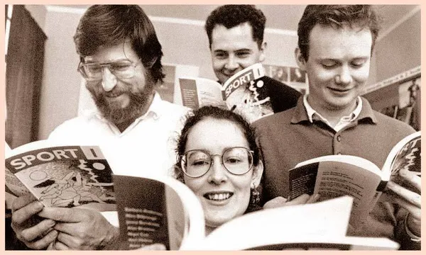 Black and white photo of four twenty-something writers (three men, one woman) sitting close together, avidly reading a literary mag.