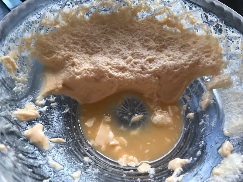A grim scene of beige / orange foamy pudding clinging to a cut-glass bowl, gross watery stuff in the bottom.