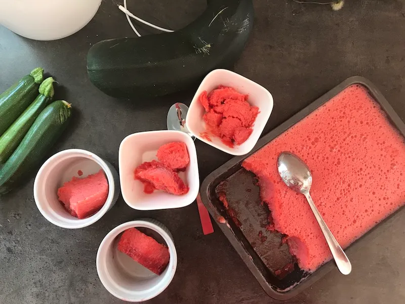 A bunch of ramekins filled with scarlet sorbet, next to a tray of same. Random courgettes all over the place, and a huge marrow.