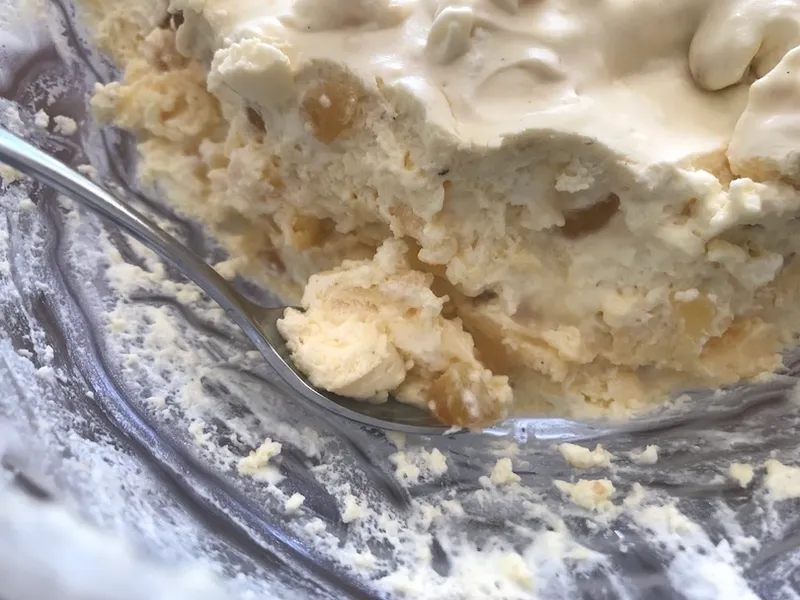 Cross section of a beige cream-based pudding, lumps of ginger visible.