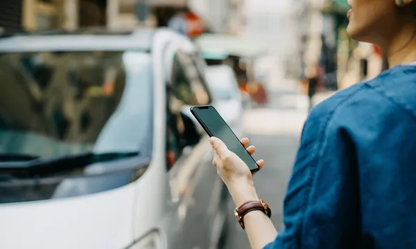 Woman ordering a taxi ride with mobile app on smartphone in the city