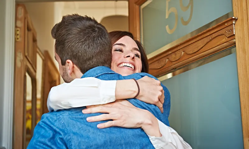 Friends hugging at front door