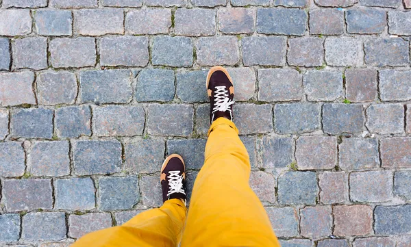 Walking on the cobbled street in sneakers, personal perspective high angle view