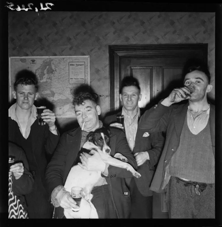 Men, and a dog, in the Denniston Hotel. Pascoe, John Dobree, 1908-1972 :Photographic albums, prints and negatives. Ref: 1/4-001245-F. Alexander Turnbull Library, Wellington, New Zealand. http://natlib.govt.nz/records/22380772.