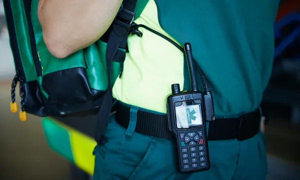 Midsection of female paramedic with walkie-talkie on belt in parking lot