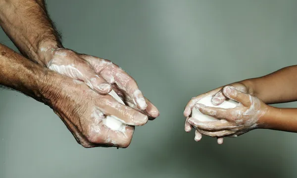 Grandfather and grandson (6-7) washing hands with bar of soap, close-up