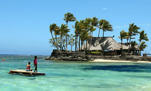 Melanesian children float on a bamboo po