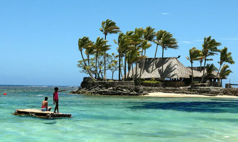 Melanesian children float on a bamboo po