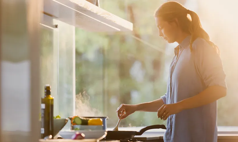 Woman cooking at stove in sunny kitchen