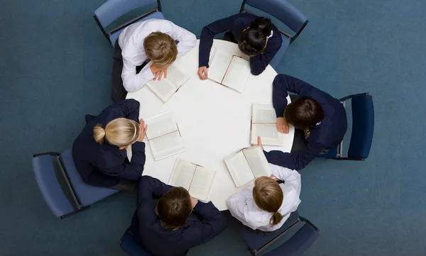 Students reading at round table in school library